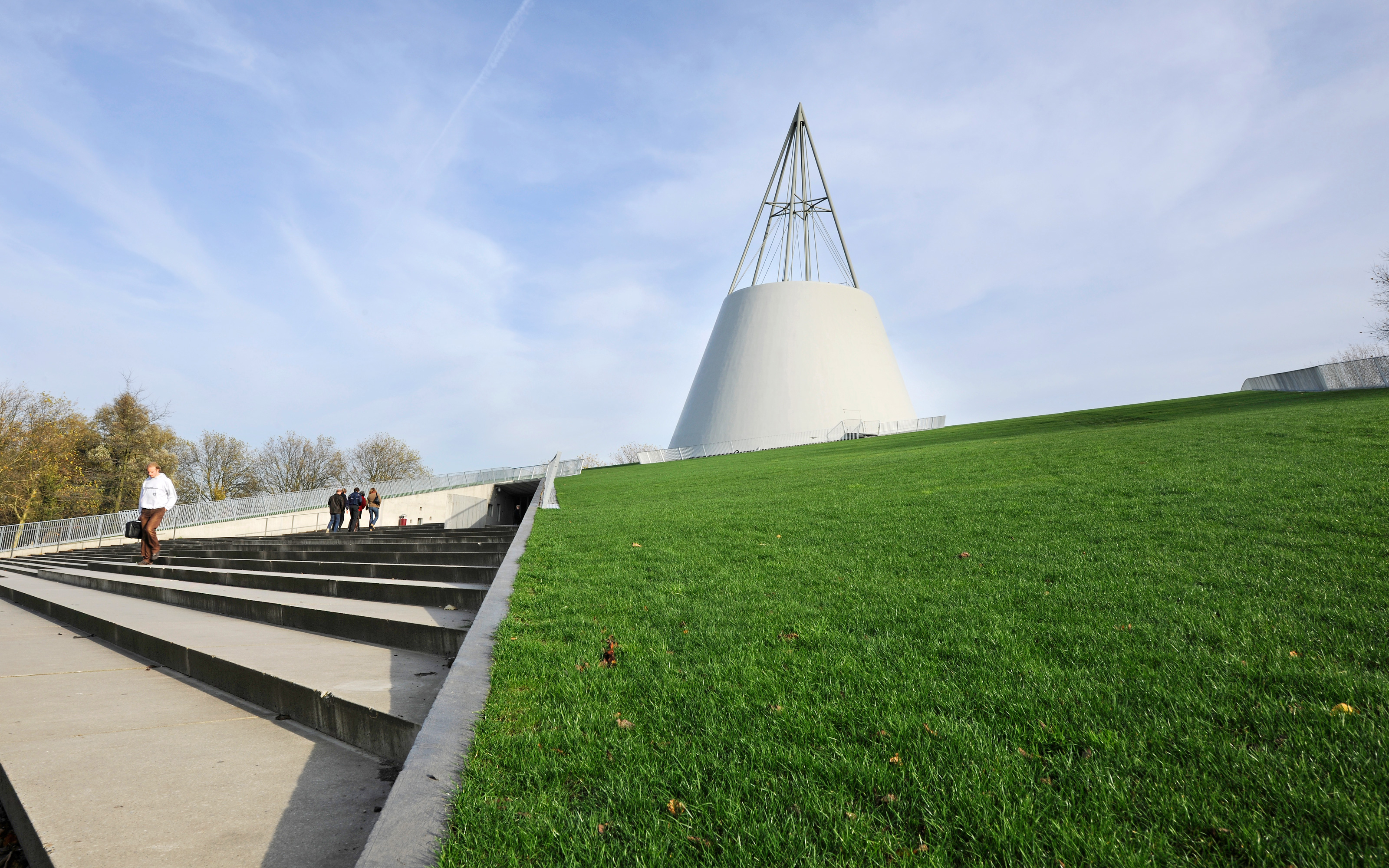 A broad flight of steps leads up to the entrance under the green roof. Pitched green roof with lawn